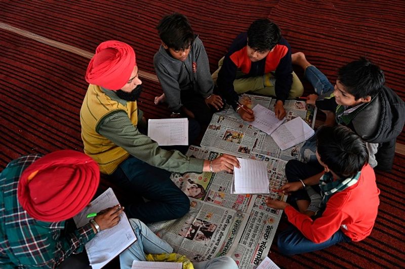 कृषि कानूनों के खिलाफ सिंघु बॉर्डर पर विरोध प्रदर्शन में शामिल किसान आस-पास के गांव के बच्चों को पढ़ाते हुए। समय मिलने पर बीच-बीच में ये किसान बच्चों को पढ़ाने के लिए चले जाते हैं।