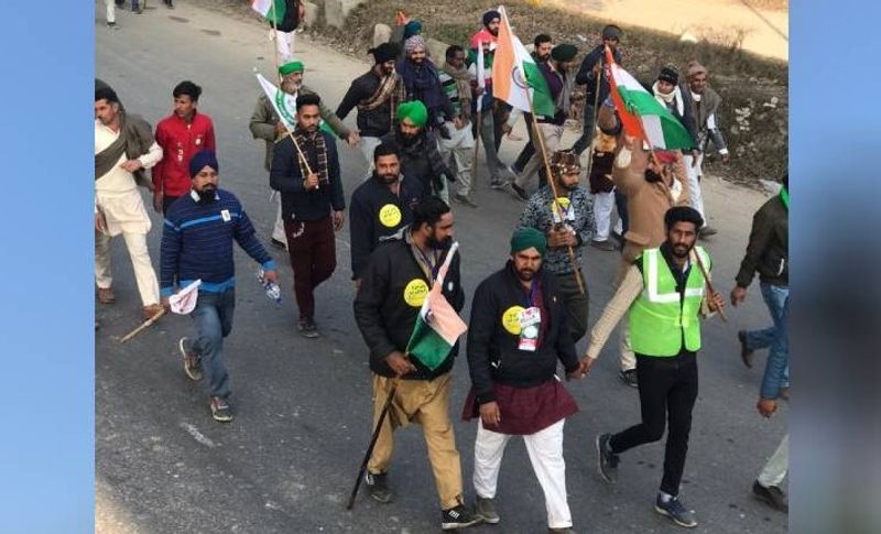 किसानों के ट्रैक्टर परेड की यह तस्वीर टीकरी बॉर्डर की है, जहां कुछ किसान पैदल ही मार्च पर निकल पड़े हैं। उन्होंने हाथ में तिरंगा पकड़े हुए है, जहां भी उनको देशभक्ति गानों की गूंज सुनाई देती है वो नाचने लगते हैं।