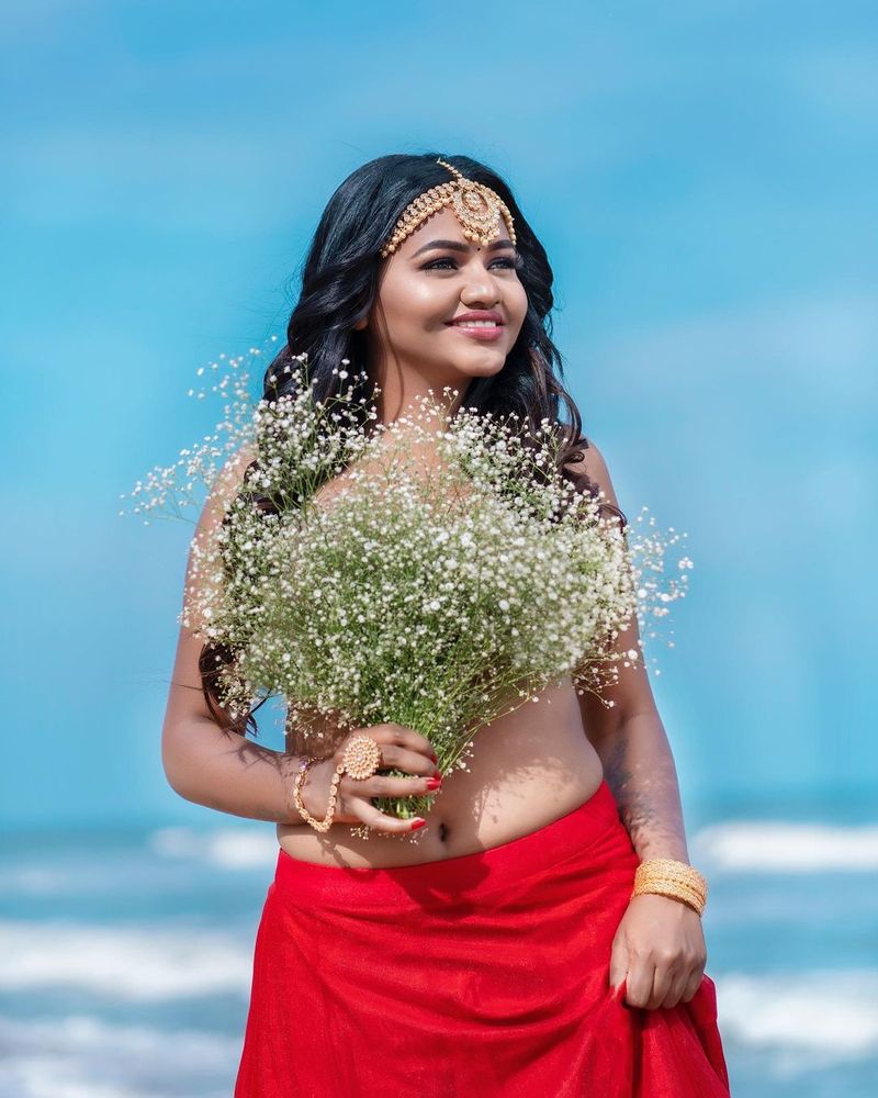மேலாடையின்றி சிவப்பு நிற பாவாடை மட்டும் அணிந்திருக்கும் ஷாலு ஷம்மு, தன் முன்னழகை கையில் உள்ள மலர் கொத்து கொண்டு மறைத்தபடி உச்சகட்ட போஸ் கொடுத்துள்ளார். 
