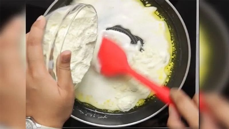 इसके बाद इसमें थोडा-थोडा करके मिल्क पाउडर डालें और लगातार चलाते जाएं। ध्यान रहे कि हमे इकठ्ठा मिल्क पाउडर नहीं डालना है, नहीं तो इसमें गुठलियां पड़ जाएंगी।