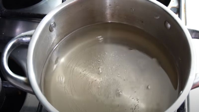 अब चाशनी में थोड़ा-थोड़ा करके गर्म पानी डालते जाएं और मिलाते जाएं, ताकि चाशनी उबलनी बंद हो जाए।