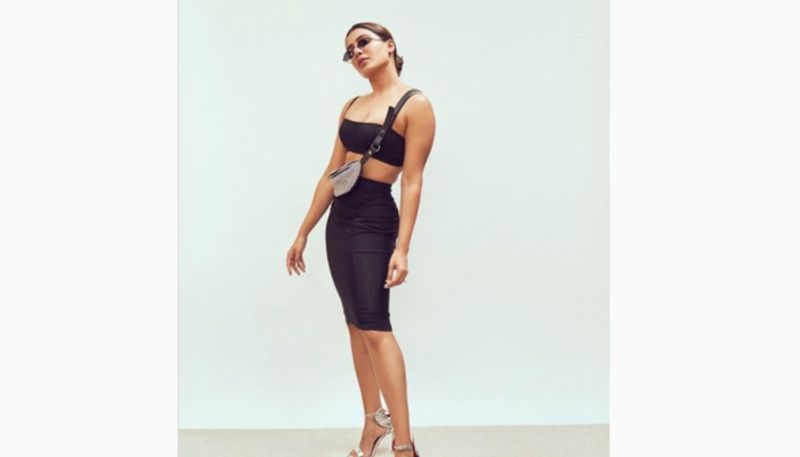 Sam dons a dark blue two-piece ensemble and styled with a contrasting silver Alexander Wang Rhinestone Mini Fanny Pack and strappy heels.