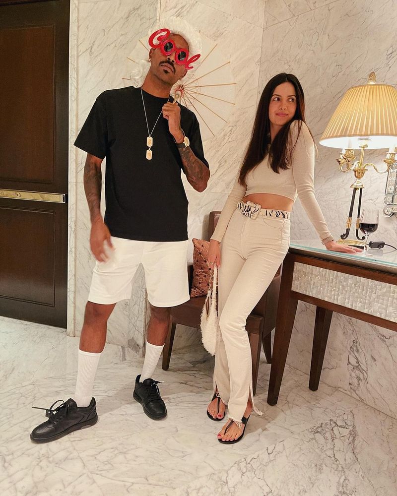 Recently, a fresh set of images was shared by Natasa. In the first photo, Pandya is seen wearing a funny white wig and toy specs on his eyes that reads 'Cool', besides possessing a small white umbrella, as Natasa looks away, partly confused.