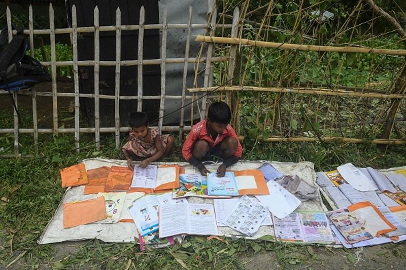 ঝড়ে ভেঙে যাওয়া, বৃষ্টিতে ভিজে ন্যাতন্যাতে পাঠ্যবই শুকিয়ে নিয়ে ফের পড়াশোনা করতে উদ্যোগী দুই খুদে।