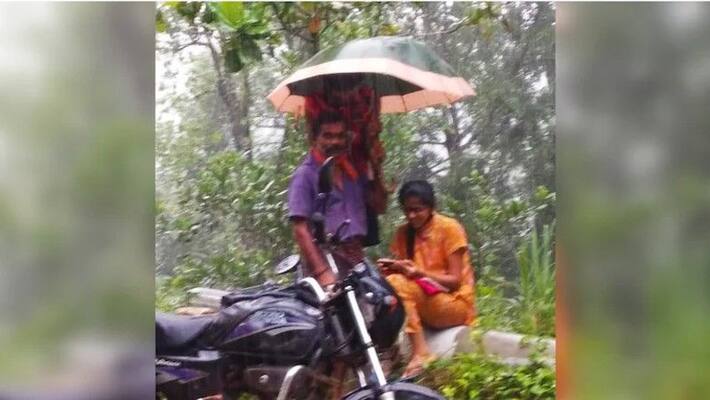 father holds umbrella to daughter as she attends online class by the road father holds umbrella to daughter as she attends online class by the road