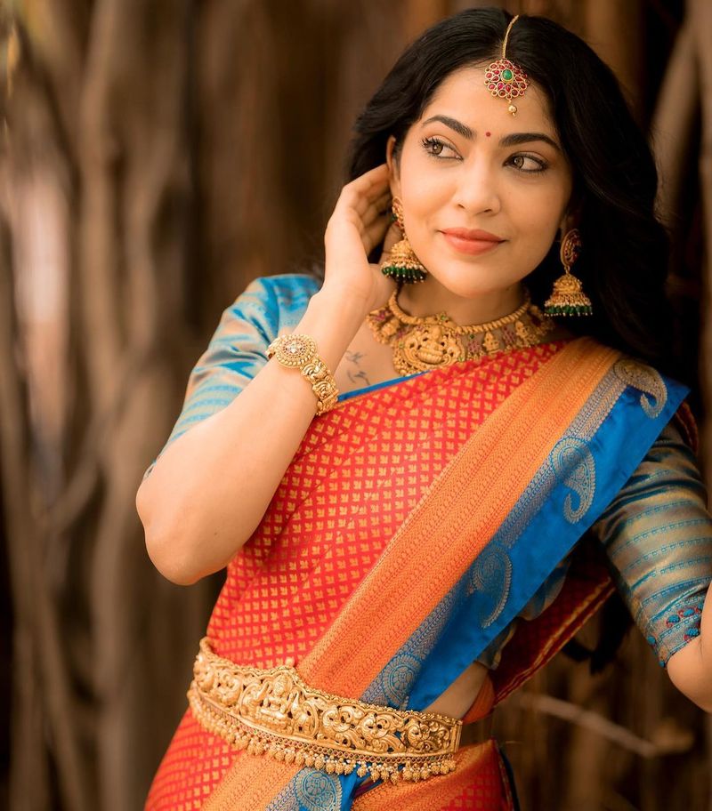 பளீச் என மின்னும் செந்தாமரை பூ போல் பட்டு சேலையில் ஜொலிக்கிறார்.