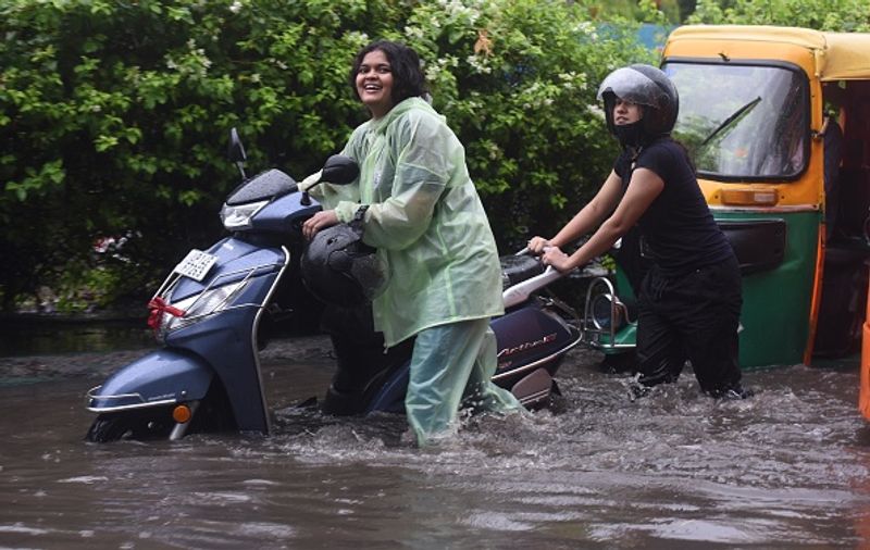 വെള്ളക്കെട്ടിനെ തുടര്ന്ന് സ്കൂട്ടര് തള്ളിക്കൊണ്ട് പോകുന്നവര്. 