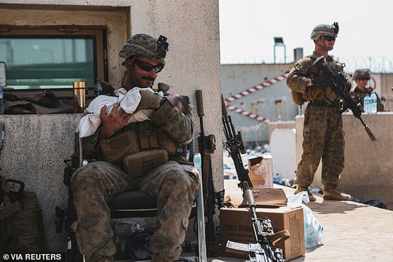 iconic photo baby lifted over wall at Kabul airport by Marine