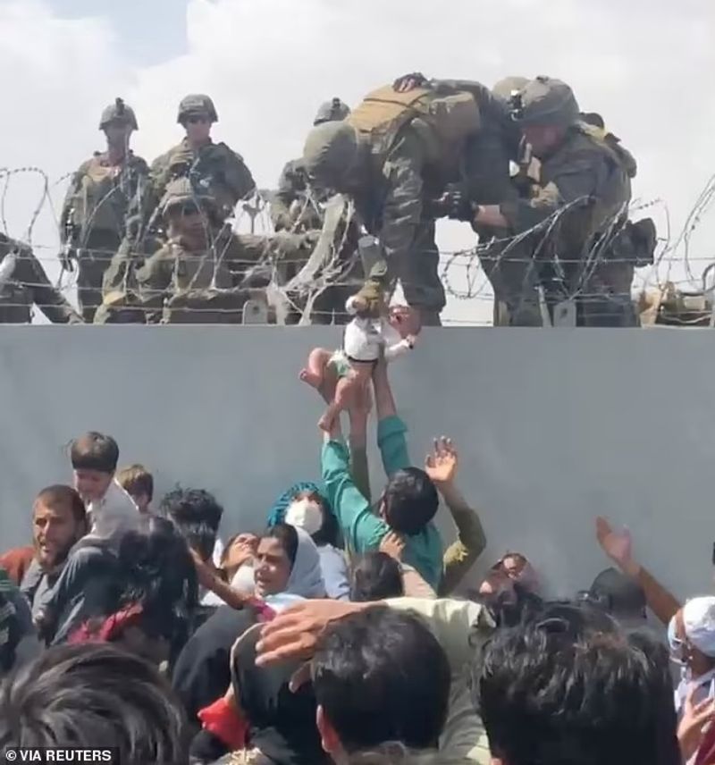 iconic photo baby lifted over wall at Kabul airport by Marine