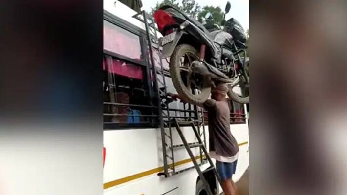 man carries heavy motorbike on his head and climbs a ladder man carries heavy motorbike on his head and climbs a ladder