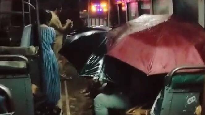 Pouring rain! Passengers holding umbrellas inside the bus!